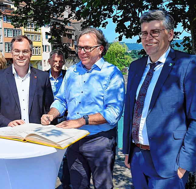 In Laufenburg trägt sich Regierungspräsident Carsten Gabbert (Mitte) auf der Laufenbrücke ins Goldene Buch der Stadt ein. Neben ihm ...