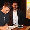Lukas Dauser trägt sich ins Goldene Buch der Gemeinde ein. Christoph Stolz freut sich darüber.