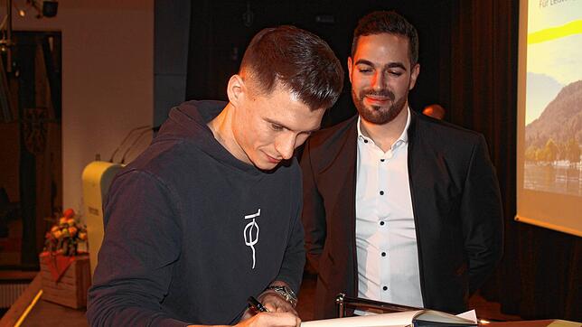 Lukas Dauser trägt sich ins Goldene Buch der Gemeinde ein. Christoph Stolz freut sich darüber.