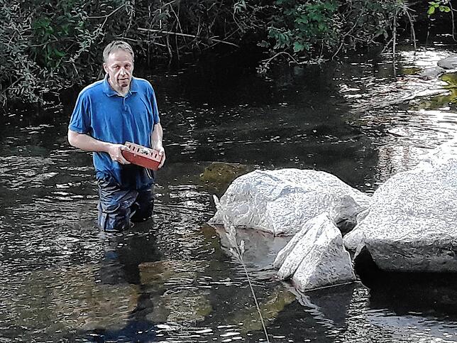 Peter Engler vom Angelsportverein Schopfheim versenkt mit Sonden versehene Backsteine in der Wiese.