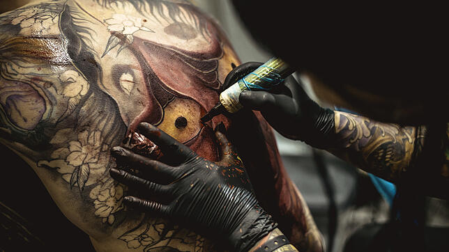 Ein Mann lässt sich tätowieren (Symbolbild). Experten befürchten negative Folgen der Tattoos.