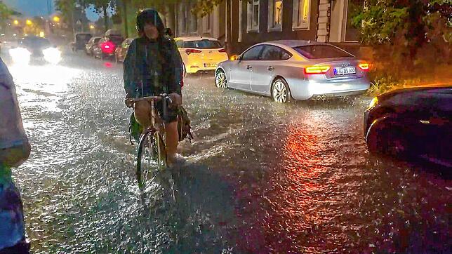 Freiburg im Breisgau: Ein Fahrradfahrer fährt über eine vom Regen überschwemmte Straße.