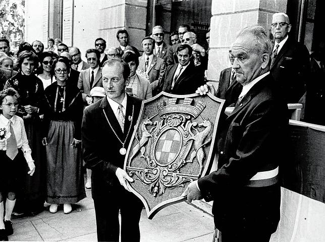 Franz Ziwey und Jean Morin halten das Stadtwappen von La Roche hoch. Es wurde aufgenommen anlässlich der Begründung der Partnerschaft am ...