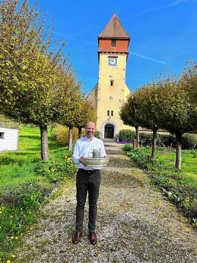 Pfarrer Florian Bosch mit Schale und Kanne für die Fußwaschung am Gründonnerstag vor der alt-katholischen Kirche in Dettighofen.