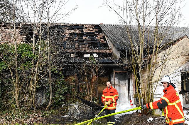 Nach dem Einsatz rollen die Feuerwehrleute die Schläuche auf. Im Hintergrund der stark beschädigte Teil des Gebäudes, an dem Nebenraum ...