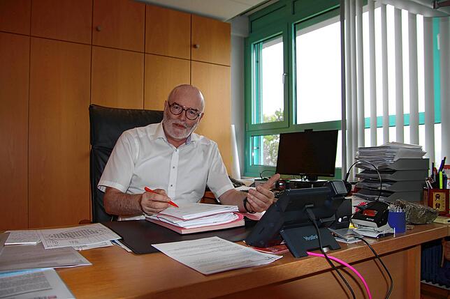 Bürgermeister Rainer Stolz beim Unterzeichnen von Akten an seinem Schreibtisch im obersten Stockwerk des Rathauses.
