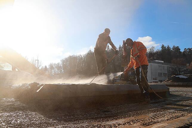 Mitarbeiter reinigen auf der Baustelle einen bereits fertiggestellten Teil des Kreisverkehrs an der Auffahrt Richtung Lindau.