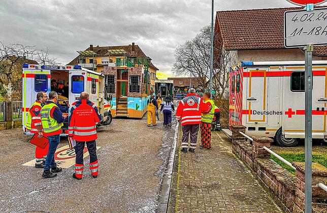 Rettungswagen, Karnevalisten und Einsatzkräfte stehen in der Nähe der Unfallstelle.