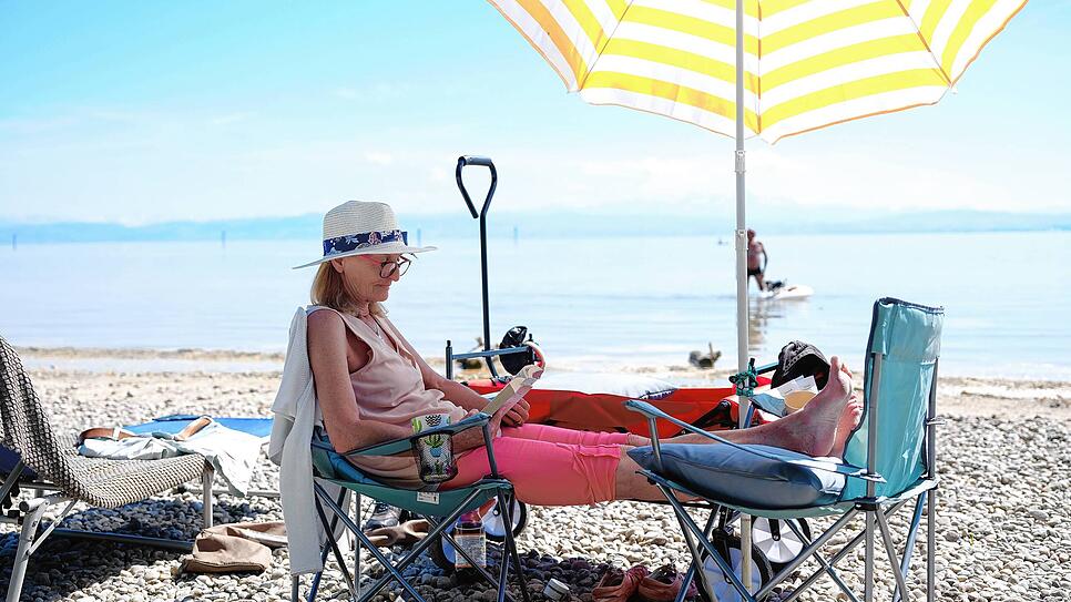 Ulrike Dietz genießt ein Buch im Schatten ihres Sonnenschirms an einem ihrer absoluten uralten Lieblingsplätze am Strandabschnitt neben ...
