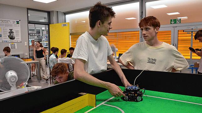Aleksandar Vladimirov (links) und Pascal Gärtner bringen einen Fußball-Roboter aufs Spielfeld. Die technikaffinen Mitglieder der ...