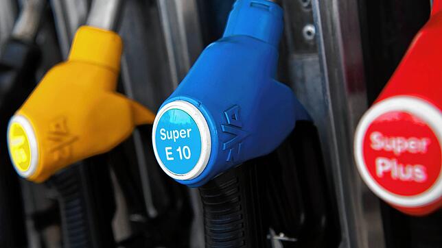 Zapfpistolen für verschiedene Kraftstoffarten, darunter auch E10, hängen an einer Zapfsäule an einer Tankstelle. Benzin und Diesel sind ...