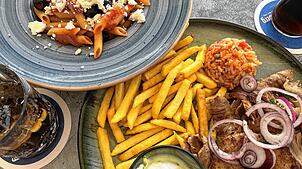 Oben Pasta auf griechische Art mit Zwiebeln, Peperoni und Schafskäse zubereitet, unten ein Menü mit Gyros, Schweinesteak, Pommes Reis ...