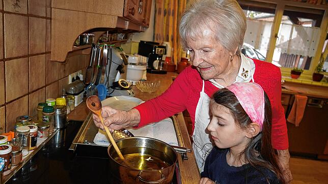 Wenn sich kleine Perlen am Holzstil bilden, können die Fasnetsküchle gebacken werden, erklärt Sofie Schellinger ihrer Urenkelin Marie.