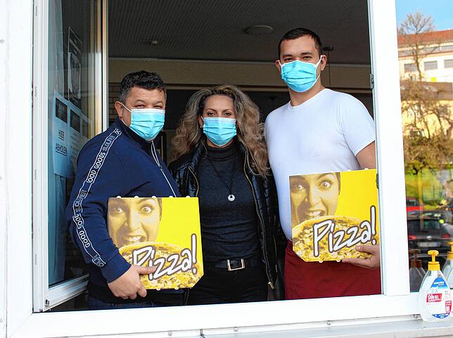 Am Fenster begrüßen Oliver und Tanja Guffler sowie Pizzabäcker Robert Tadic derzeit die Kunden, da nur das Abholen der Speisen erlaubt ist.