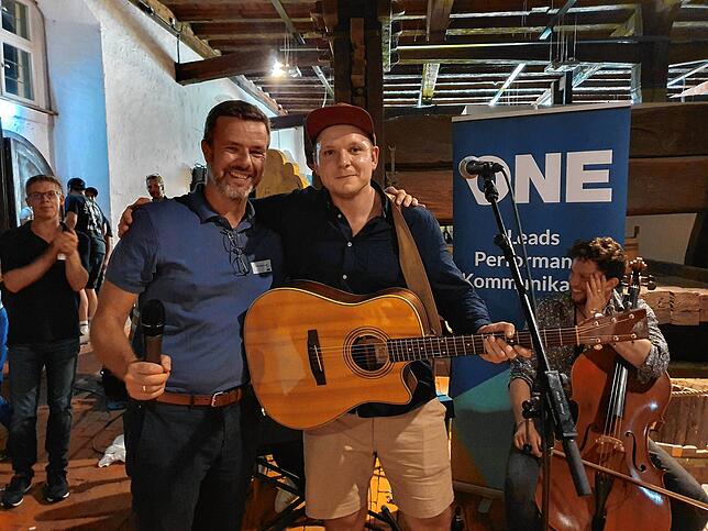 Geschäftsführer Michel Bieler-Loop (SÜDKURIER-Medienhaus und SK One, links) mit Bandleader Peter Pux im Torkel in Salem an.