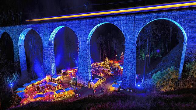 Die Höllentalbahn fährt 2022 über das beleuchtete Viadukt über der Ravennaschlucht, während darunter der Weihnachtsmarkt stattfindet. ...