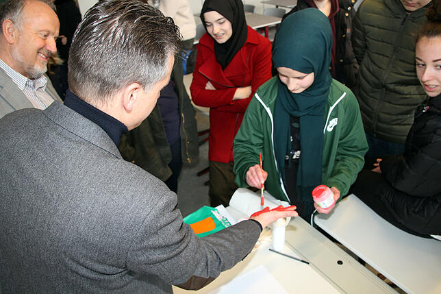 Realschülerin Meryem Erdem bemalt die Hand des Bundestagsabgeordneten Thorsten Frei für den Abdruck zum Red Hand Day. Bild: Bernhard Lutz