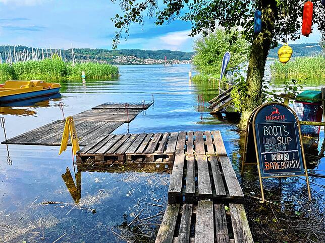 Vom Ständer mit den SUP-Boards geht es über Paletten zum See.