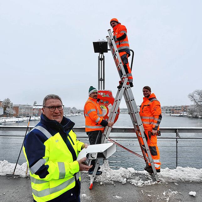 Sven Honold, Christian Koch und Jan Fischer, Mitarbeiter der Stadtreinigung, bauen eine Messstation auf der Fahrradbrücke auf, im ...