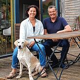 Arianne Irsslinger und Florian Armbruster mit Hund Lennox auf der Terrasse ihres Hauses.