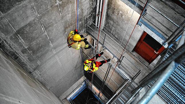 Abwärts: Ein Mitglied der Höhenrettungsgruppe (rechts) und ein Feuerwehrmann seilen sich im Inneren des Schlauchturms ab.