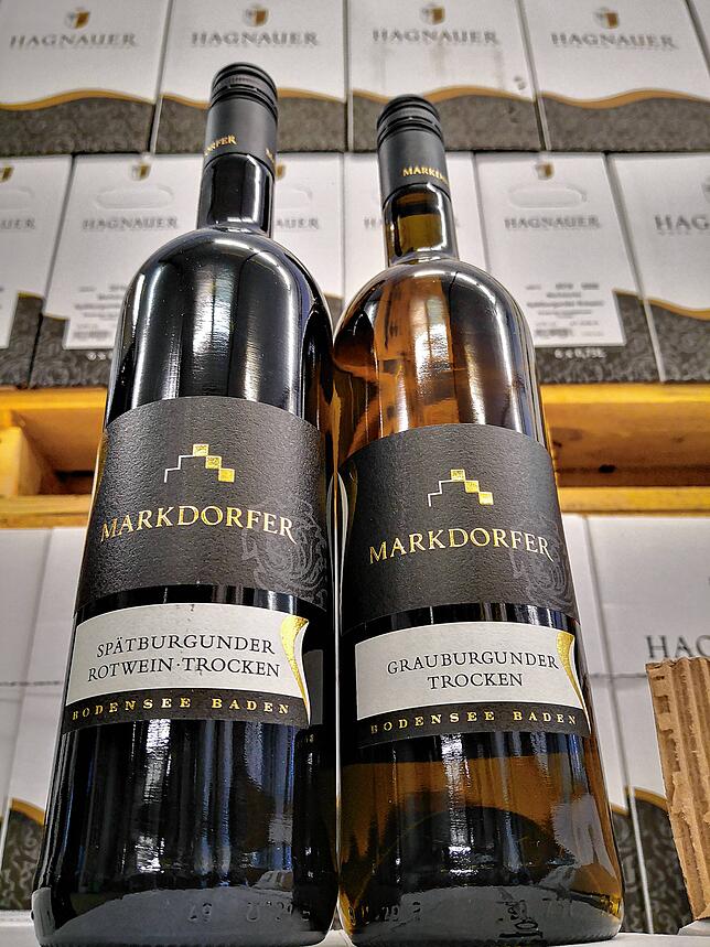 Diese Aufnahme zeigt je eine Flasche trockenen  Markdorfer Spätburgunder und trockenen Grauburgunder. Dahinter sind Sechser-Kartons auf ...