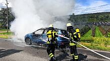 Zwei Einsatzkräfte der Feuerwehrabteilung Riedheim löschen das brennende Auto.