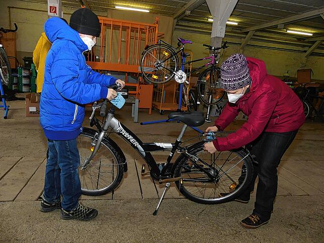 Die Flüchtlinge Denys und Anzhela Rekhta helfen mit, ihr neues Fahrrad herzurichten.