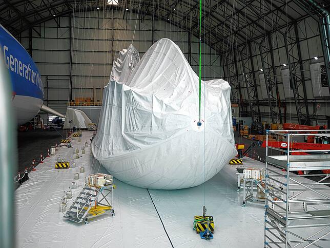 Der Zeppelin liegt nicht auf dem Boden auf, sondern ist so aufgehängt, dass die Hülle übergestreift werden kann.