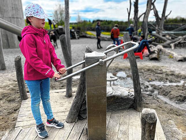 Die achtjährige Greta pumpt Wasser im Matschbereich auf dem Abenteuerspielplatz.