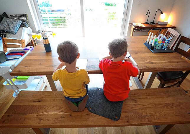 Zwei Jungen füllen zu Hause Lernbücher aus. Seit Beginn der Corona-Pandemie sitzen vor allem Geschwister enger aufeinander als je zuvor.
