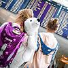 Zwei Mädchen stehen vor dem Abflug in den Urlaub mit ihren Eltern vor einer Abflugtafel am Flughafen in München. Vor Beginn der ...