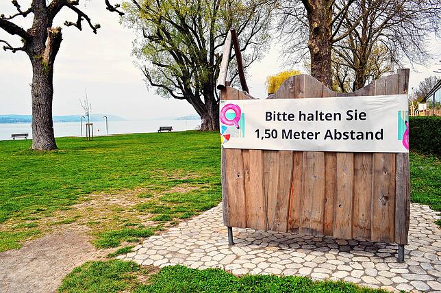 „Bitte halten Sie 1,50 Meter Abstand“, steht auf einem großen Banner an einer Umkleidekabine am Naturstrand in ...