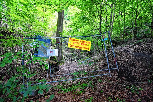 Die erste Sperrung der eigentlichen Marienschlucht an deren Fuß. Ein Stück weiter hinten steht ein großes neongelbes Banner auf einem ...
