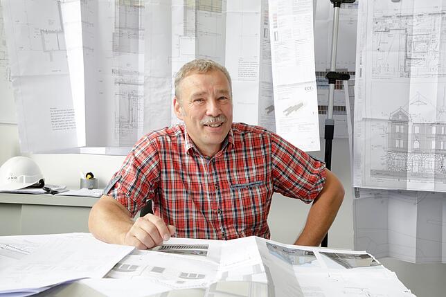 Roland Drewans in seinem Büro, vor den Plänen der neuen alten Fassade.