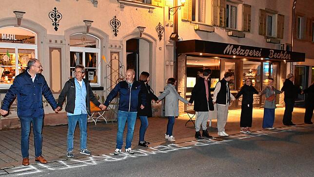 Rund 100 Menschen bilden eine Menschenkette in der Hauptstraße.