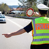 18.04.2018, Bayern, Wolfratshausen: Ein Polizist winkt ein Fahrzeug von der Bundesstraße zu einer Kontrollstelle der Polizei auf den ...