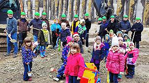 Während im Hintergund viele der Planer und Unternehmer der ersten Stunde den Spaten mit Erde in die Luft recken, buddeln die Kinder ...
