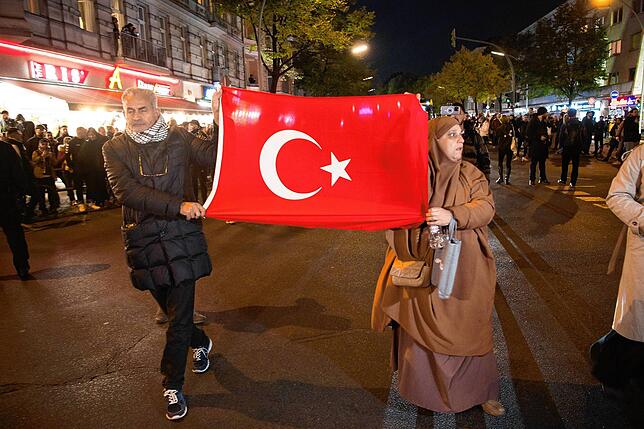 Teilnehmer einer verbotenen Pro-Palästina-Demonstration halten auf der Sonnenallee im Berliner Bezirk Neukölln ein türkische Flagge.
