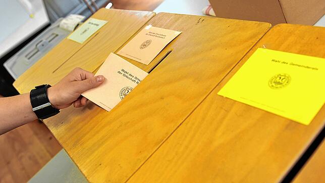 Ein Mann wirft in einem Wahllokal in Baden-Württemberg seinen Stimmzettel für die Wahl des Ortschaftsrates in eine Wahlurne. Bild: ...