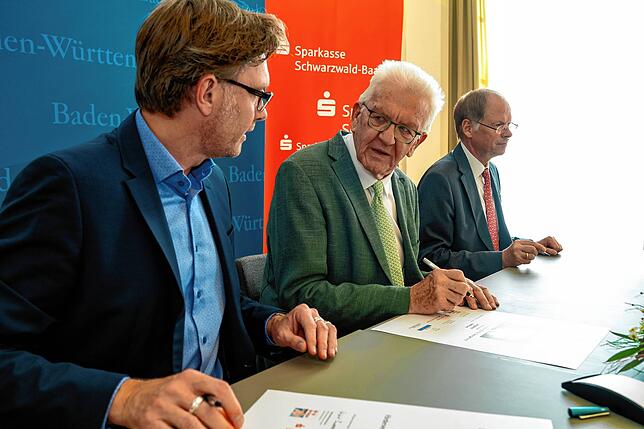 Stefan Lutz, Ministerpräsident Winfried Kretschmann und Arendt Gruben (von links) bei der Unterzeichnung der Siegerurkunden.