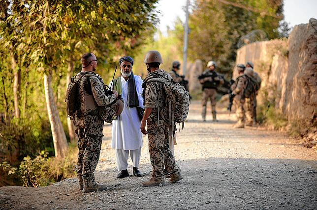 Ein Bundeswehrsoldat (links) und ein Dolmetscher (rechts) sprechen 2011 nahe Kundus mit einem Afghanen.