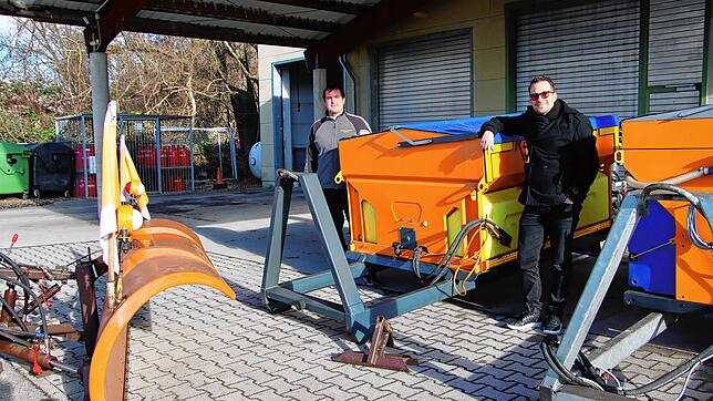 Ralf Wiedemann, Winterdienst-Einsatzleiter (links) und Ferdi Cihan, Leiter der Technischen Betriebe stehen neben Winterdienst-Aufsätzen ...