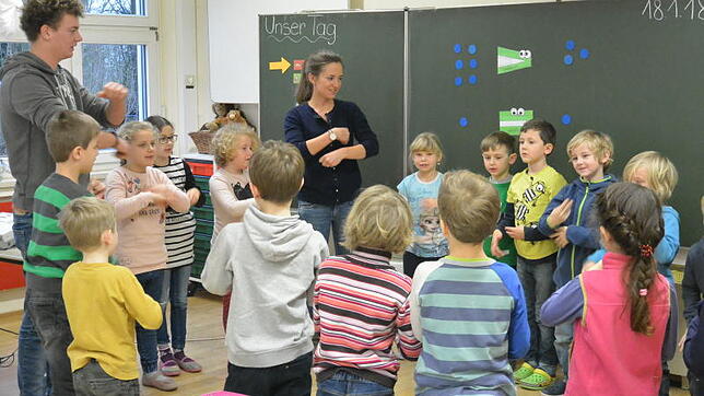 Ehe der Unterricht losgeht, singt die erste Klasse von Sara Baur ein gemeinsames Lied, FSJler Marco Beisert unterstützt sie.