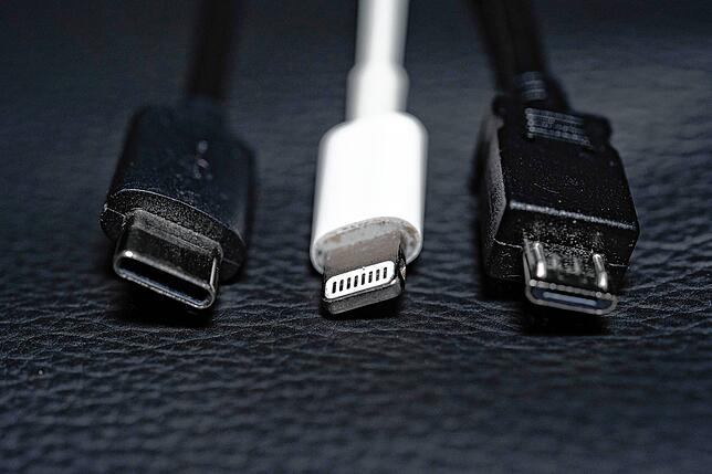 Ein USB-C, ein Apple Lightning und ein Micro-USB Kabel (von links nach rechts) liegen nebeneinander zu sehen. Für neue Geräte wird es ...