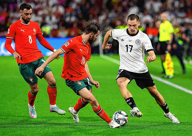 Deutschlands Florian Wirtz (r) in Aktion gegen Portugals Spieler Bruno Fernandes (l) und Bernardo Silva.
