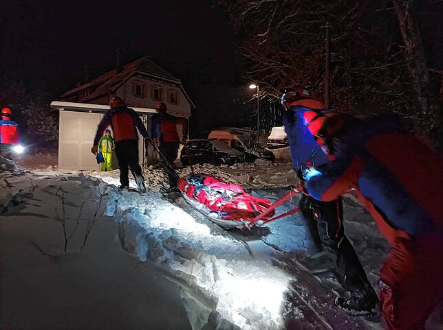 Einsatzkräfte der Bergwacht transportieren eine mit dem Schlitten verunglückte Frau zum Rettungswagen.