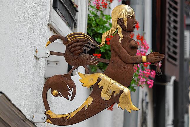 Mit goldenen Details zieht diese Nixe die Blicke auf sich. Wer weiß, an welcher Wand sie angebracht ist?