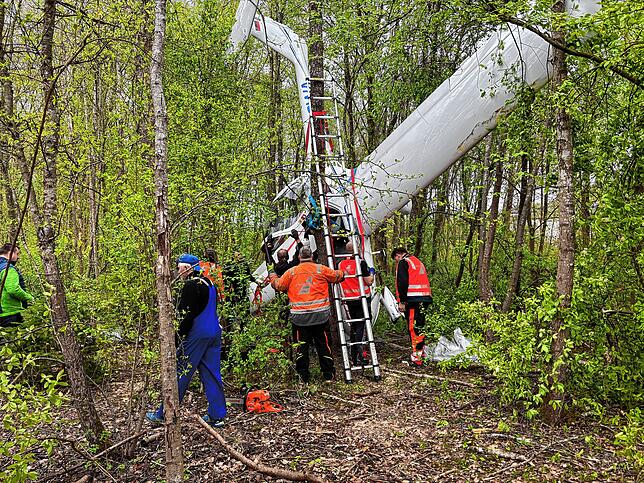 Kopfüber hängt das Flugzeugwrack in einem kleinen Wäldchen an der B27 fest. Mitarbeiter eines Abschleppunternehmens und Mitglieder der ...