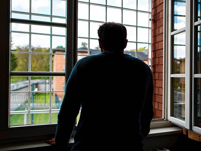 Ein Straftäter steht vor einem vergitterten Fenster in der Klinik für Forensische Psychiatrie (Maßregelvollzug) auf dem Gelände des ...